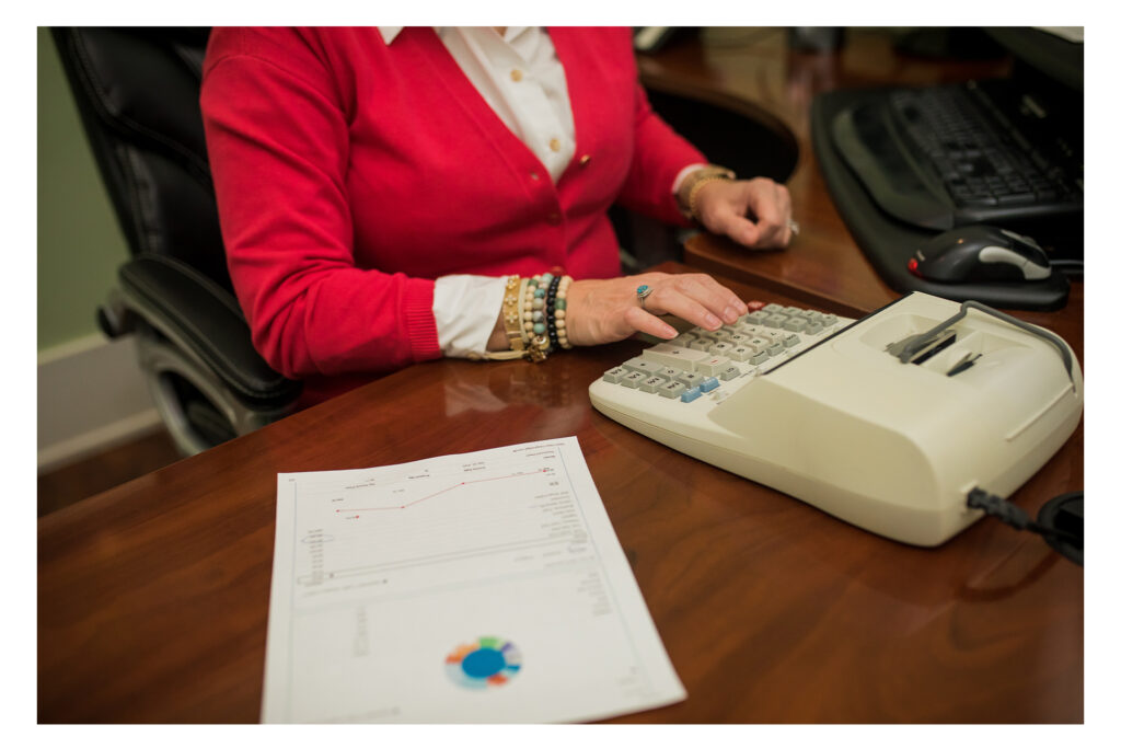 A woman tabulating financial data on a large calculator